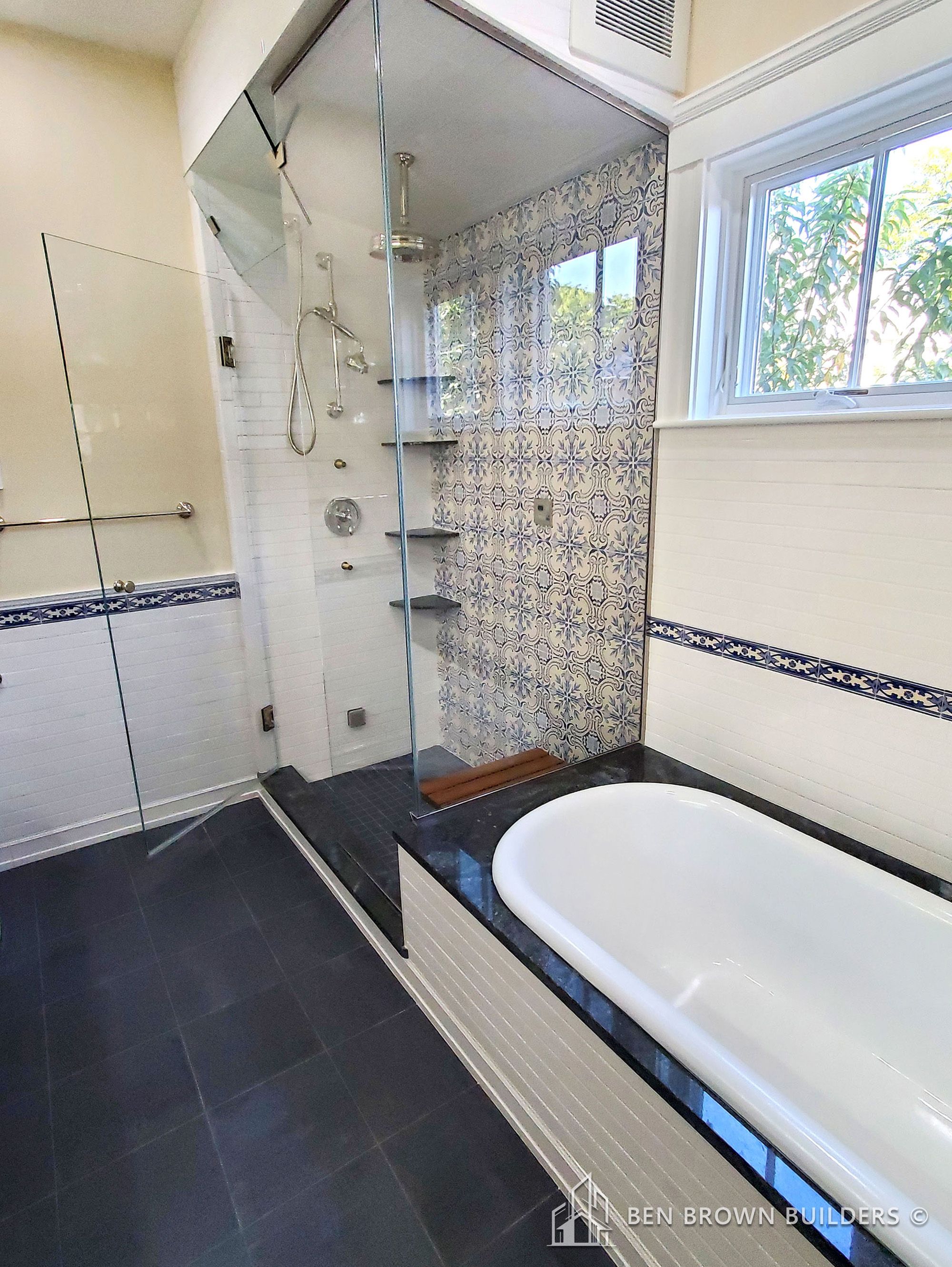 Luxurious bathroom with a freestanding white tub, patterned blue accent wall, and a separate glass shower